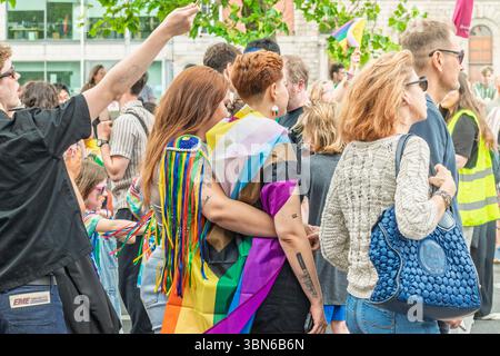 Une jeune femme dans des vêtements colorés avec des épaulettes brillantes embrasse une autre femme pendant Dublin Pride Parade. 28 juin 2025 Banque D'Images