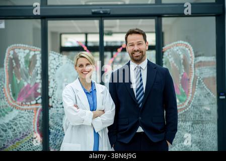 Directeur d'hôpital masculin debout à côté d'un médecin féminin, cadre médical. Banque D'Images