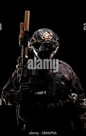 Un personnage militaire vêtu d'un équipement de combat avancé équipé d'un fusil et de lunettes de vision nocturne, mettant l'accent sur la sécurité, l'expertise tactique et l'anonymat Banque D'Images