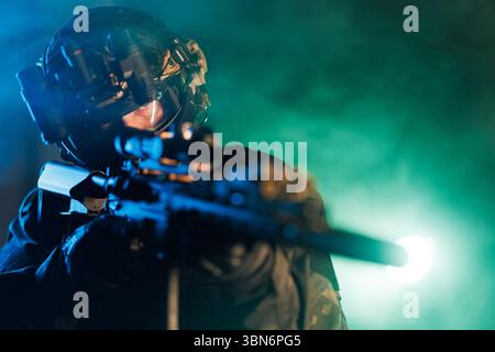 Un membre de l'équipe des forces spéciales équipé d'un équipement tactique avancé dans une opération secrète la nuit. L'opérateur vise à travers une lunette de tir, surrou Banque D'Images