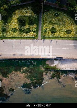 Une photo aérienne de la promenade de New Brighton, montrant la route, une prairie de fleurs sauvages animée et la rencontre de la terre et de la mer. Banque D'Images