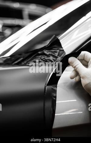 L'application d'habillage modifie l'apparence du véhicule. Emballage en vinyle pour voiture à panneau complet. L'installation à grande échelle de film vinyle transforme l'extérieur du véhicule Banque D'Images