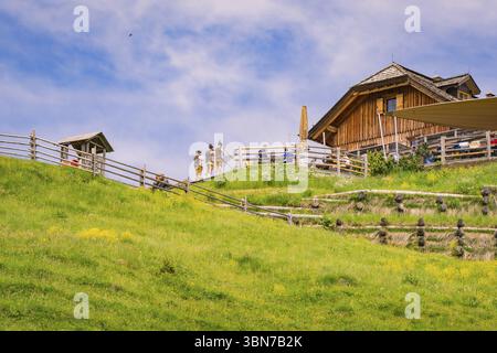 Une cabane en bois se dresse sur une pente herbeuse, entourée de structures traditionnelles en bois, Zallinger Alm, Dolomites, Italie, Europe Banque D'Images