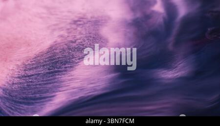 Flux de mélange. Eau de couleur. Émulsion humide de peinture liquide fluide violet rose défocalisée se répandant sur fond acrylique créatif d'art abstrait. Banque D'Images
