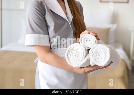 Femme de chambre avec des serviettes roulées dans la chambre d'hôtel, gros plan Banque D'Images