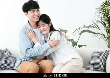 Jeune couple embrassant sur le canapé Banque D'Images