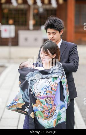 En juin 2025, un couple japonais dans la vingtaine visite un sanctuaire à Aichi pour l'omiyamairi de leur bébé. Le père aide doucement la mère à mettre un Banque D'Images