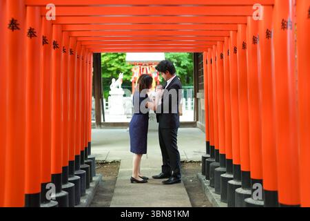 En juin 2025, un jeune couple japonais dans la vingtaine avec son bébé d’un mois passe un moment tranquille près de la porte torii d’un shrin Inari Banque D'Images