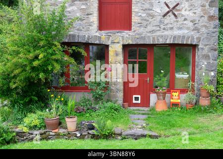 Vue extérieure avant du chalet de maison de grange converti avec porte rouge et pots de jardin dans Carmarthenshire pays de Galles Royaume-Uni Grande-Bretagne Royaume-Uni KATHY DEWITT Banque D'Images