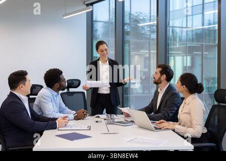Un groupe diversifié de professionnels des affaires collaborant dans une salle de réunion de bureau moderne, discutant de stratégie et d'idées. Banque D'Images