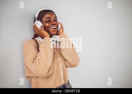 Portrait de la jeune femme noire qui envoie des messages sur smartphone. Banque D'Images