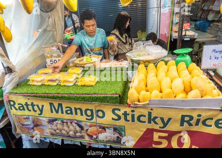Un vendeur vend du riz collant à la mangue à un étal de rue avec le signe, marché de Pratunam, Ratchathewi, Bangkok, Thaïlande Banque D'Images