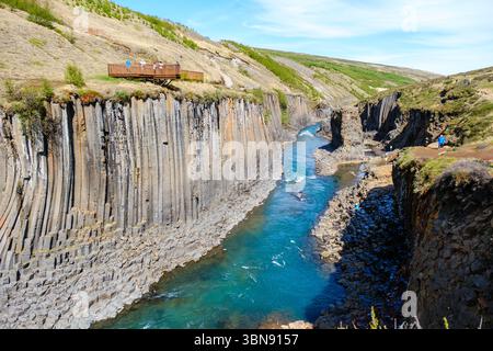 Explorez le paysage époustouflant du canyon de Studlagil en Islande, avec des colonnes de basalte saisissantes et une rivière bleue éclatante qui coule dans la gorge. Banque D'Images
