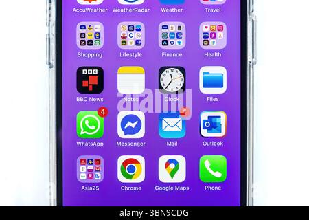 iphone 14 pro écran smartphone montrant diverses applications populaires messagerie, WhatsApp, navigation et outils météo sur un fond violet bulles de message Banque D'Images