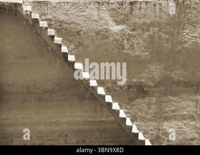 Fond avec un vieux mur sale et des escaliers qui courent le long de lui en diagonale Banque D'Images