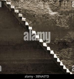 Fond avec un vieux mur sale et des escaliers qui courent le long de lui en diagonale Banque D'Images