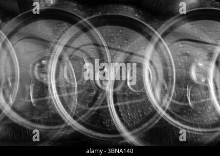 Vue abstraite en gros plan de trois canettes de boisson en mouvement sur fond noir. Banque D'Images