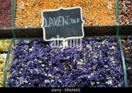 Istanbul, Turquie. La plus grande ville de Turquie et l'une des rares villes transcontinentales au monde, couvrant à la fois l'Europe et l'Asie à travers le détroit du Bosphore., Un spectacle vibrant de fleurs séchées, probablement de lavande, dans un cadre de marché. Les fleurs sont de couleur pourpre foncé et sont densément emballées ensemble, créant un arrangement texturé et visuellement attrayant. L'affichage est logé dans un récipient en verre, qui fait partie d'un plus grand affichage de diverses épices et herbes séchées. Le récipient en verre est divisé en sections, les fleurs de lavande étant les plus proéminentes. Un petit panneau de tableau avec le Banque D'Images