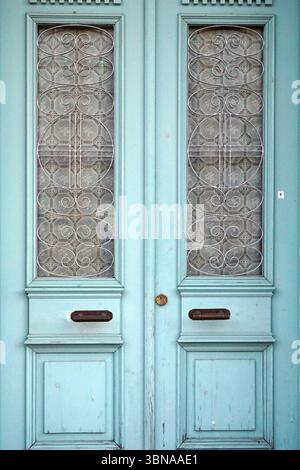 Une paire de portes doubles avec une couleur bleu clair ou sarcelle. Les portes comportent une grille décorative en métal sur le dessus, qui est ornée d'un motif répétitif de petites formes circulaires ou ovales. Les portes ont un aspect légèrement vieilli ou altéré, avec une petite poignée de porte, peut-être en laiton, visible sur la porte droite. Les portes sont placées dans un cadre bleu clair ou sarcelle avec une bordure décorative. Le bas des portes a une petite poignée de porte, peut-être en laiton. Les portes sont légèrement entrouvertes, révélant un aperçu de l'intérieur. Un œil d'artiste et l'imagination façonné légende., Nicosie (Lefkosia), Chypre, le monde Banque D'Images
