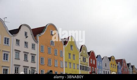Schärding, le charmant joyau baroque près de la rivière Inn en haute-Autriche. Connu pour la rangée colorée baroque “Silberzeile” de maisons de guilde pastel et des murs médiévaux et portes bien conservés., Une rangée de bâtiments colorés avec des toits à pignons. Les bâtiments sont peints dans une variété de couleurs vibrantes, y compris jaune, orange, rouge, bleu, et blanc, et sont disposés de façon linéaire. La perspective est d'un angle bas, regardant les bâtiments, ce qui crée un sentiment de grandeur et d'échelle. Le ciel est couvert, projetant une douce lumière sur la scène. Au premier plan, une statue d'une personne est visible, Banque D'Images