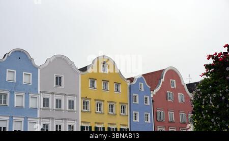 Schärding, le charmant joyau baroque près de la rivière Inn en haute-Autriche. Connu pour la rangée colorée baroque “Silberzeile” de maisons de guilde pastel et des murs médiévaux et portes bien conservés., Une rangée de bâtiments colorés avec des toits à pignons. Les bâtiments sont peints dans des tons de bleu, jaune, rose et blanc, et sont ornés de boîtes à fleurs et de panneaux. La perspective est du niveau de la rue, en regardant les bâtiments, ce qui crée une sensation de profondeur et d'échelle. Le ciel est couvert, et l'atmosphère générale est calme et sereine. Un arbre avec des fleurs rouges est visible sur le côté droit du Banque D'Images