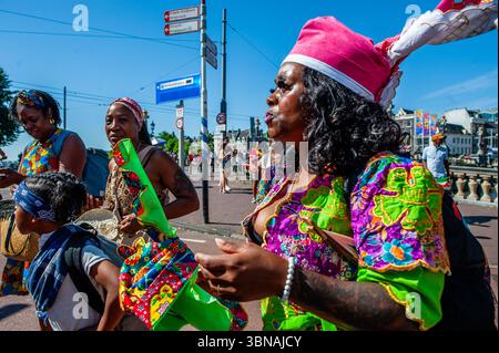 Amsterdam, pays-Bas. 01 juillet 2025. Des femmes surinamaises sont aperçues arrivant au défilé. Le 1er juillet 1863 marque la fin de l’esclavage pour les Surinamais. Ce défilé fait partie du festival 'Keti Koti' ('chaînes brisées' en Surinamais), qui est ouvert par un défilé coloré en vêtements traditionnels appelé Bigi Spikri. Crédit : SOPA images Limited/Alamy Live News Banque D'Images