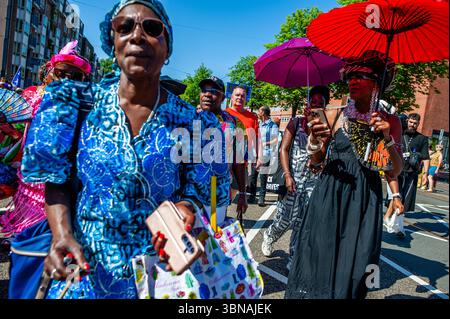 Amsterdam, pays-Bas. 01 juillet 2025. On voit des femmes tenir des parapluies à cause de la canicule. Le 1er juillet 1863 marque la fin de l’esclavage pour les Surinamais. Ce défilé fait partie du festival 'Keti Koti' ('chaînes brisées' en Surinamais), qui est ouvert par un défilé coloré en vêtements traditionnels appelé Bigi Spikri. Crédit : SOPA images Limited/Alamy Live News Banque D'Images