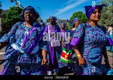 Amsterdam, pays-Bas. 01 juillet 2025. Des femmes surinamaises en robes violettes sont vues danser. Le 1er juillet 1863 marque la fin de l’esclavage pour les Surinamais. Ce défilé fait partie du festival 'Keti Koti' ('chaînes brisées' en Surinamais), qui est ouvert par un défilé coloré en vêtements traditionnels appelé Bigi Spikri. Crédit : SOPA images Limited/Alamy Live News Banque D'Images
