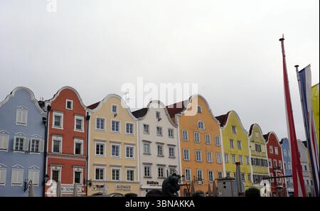 Schärding, le charmant joyau baroque près de la rivière Inn en haute-Autriche. Connu pour la rangée colorée baroque “Silberzeile” de maisons de guilde pastel et des murs médiévaux et portes bien conservés., Une rangée de bâtiments colorés avec des toits à pignons, debout dans une rangée. Les bâtiments sont peints dans une variété de couleurs vibrantes, y compris le bleu, le rouge, le jaune et l'orange, et sont ornés de garnitures blanches. La perspective est d'un angle bas, regardant les bâtiments, ce qui crée un sentiment de grandeur et d'échelle. Le ciel est couvert, projetant une douce lumière sur la scène. Au premier plan, une statue d'une personne est Banque D'Images