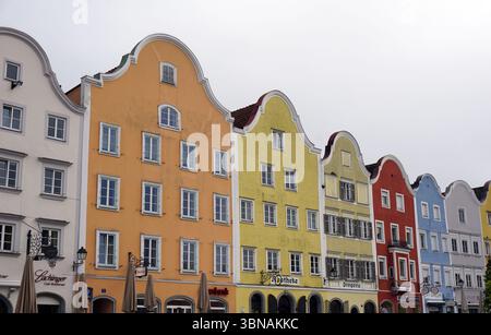 Schärding, le charmant joyau baroque près de la rivière Inn en haute-Autriche. Connu pour la rangée colorée baroque "Silberzeile" de maisons de guilde pastel et des murs médiévaux et portes bien conservés., Une rangée de bâtiments colorés avec des toits à pignons, caractéristique de l'architecture traditionnelle. Les bâtiments sont peints dans une variété de couleurs vibrantes, y compris orange, jaune, rouge, bleu, et blanc, et sont ornés de nombreuses fenêtres et signes. La perspective est du niveau de la rue, en regardant les bâtiments, ce qui crée une sensation de profondeur et d'échelle. Le ciel est couvert, projetant une douce lumière sur la scène. Banque D'Images