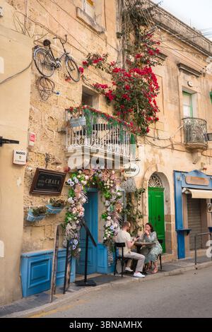 Malta Street, vue en été d'un couple assis à une table à l'extérieur d'un café-bar pittoresque dans une rue dans le centre historique de la vieille ville de Rabat, Malte Banque D'Images