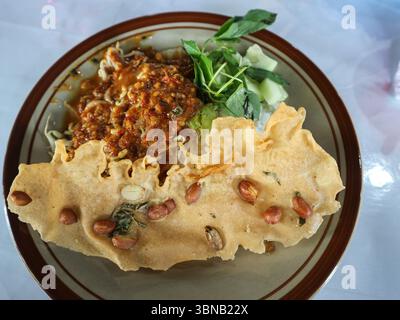 Il s’agit du pecel, un plat javanais traditionnel composé de légumes cuits à la vapeur mélangés garni d’une sauce épicée aux arachides, servi avec un rempeyek Banque D'Images