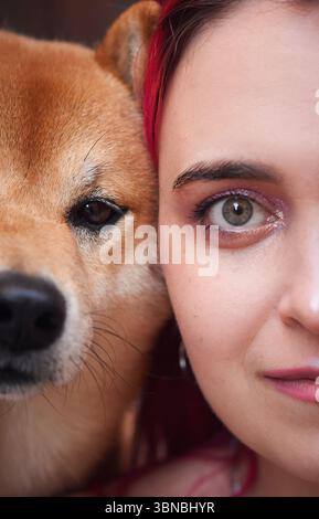 Un gros plan capture un Shiba Inu et une personne aux cheveux roses éclatants partageant un moment de sérénité. Les textures détaillées de leur environnement s'améliorent Banque D'Images