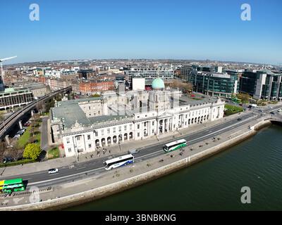 Dublin, Irlande - 9 avril 2025 - image aérienne du bâtiment Custom House le long des quais de la rivière Liffey alors que les bus passent dans le centre-ville de Dublin par un après-midi ensoleillé Banque D'Images