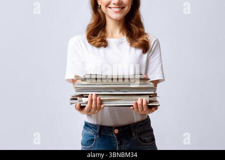 Portrait de jeune femme souriante tenant Stack of Old magazines dans les mains Banque D'Images