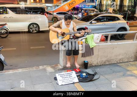 Busker aveugle, artiste de rue jouant de la guitare dans la rue, signe 'S'il vous plaît soutenir le chanteur aveugle', Bangkok, Thaïlande Banque D'Images