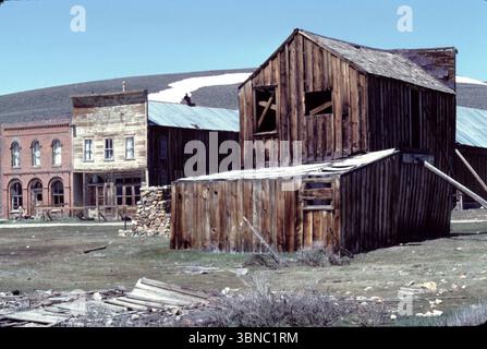 Bodie CA USA 1984. Le département de l'intérieur des États-Unis reconnaît le district historique de Bodie comme un monument historique national. Également enregistrée comme monument historique de Californie, la ville fantôme a été officiellement créée en tant que parc historique d'État de Bodie en 1962. Il reçoit environ 200 000 visiteurs par an. Bodie State Historic Park est en partie soutenu par la Fondation Bodie. En 1876, la Standard Company découvrit un gisement rentable de minerai aurifère, qui transforma Bodie, d'un camp minier isolé comprenant quelques prospecteurs et employés de la compagnie, en une ville-bourgade du Far West. Banque D'Images