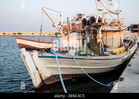 Bateau de pêche rustique vintage amarré dans un port méditerranéen tranquille au coucher du soleil Banque D'Images