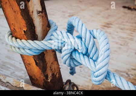 Corde bleue attachée avec un noeud nautique à une poutre en métal rouillé sur un vieux bateau Banque D'Images