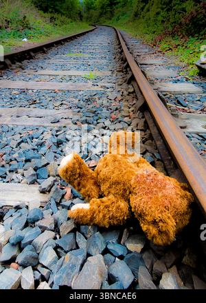 Un ours en peluche repose sur les voies d'une ligne de chemin de fer. Banque D'Images