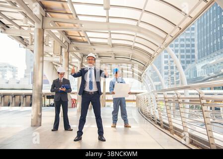 Les équipes d'ingénieurs civils se réunissant ensemble portent des casques de travailleurs casque dur sur le chantier de construction dans la ville moderne. Moteur chef de projet industriel contremaître Banque D'Images