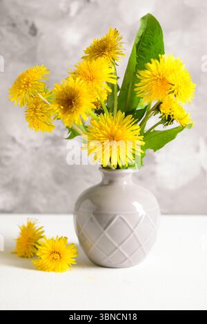 Vase avec de belles fleurs de pissenlit sur une table lumineuse sur fond de grunge Banque D'Images