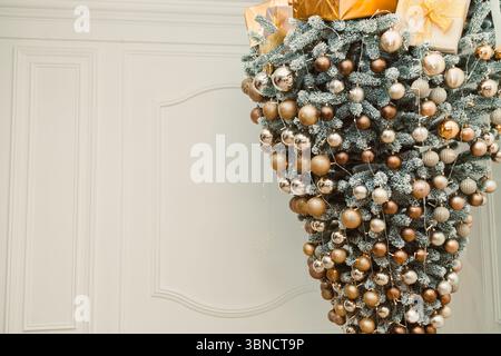 Cette saison des fêtes, un sapin de Noël artistique à l'envers orné d'ornements or et argent est complété par des cadeaux élégamment emballés, enhan Banque D'Images