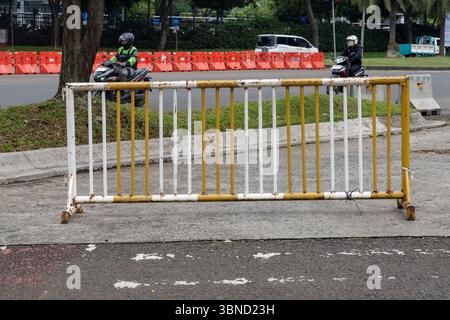 Jakarta, Indonésie - 30 janvier 2025 : clôture jaune et blanche sur le bord de la route. Une moto est garée derrière la clôture Banque D'Images