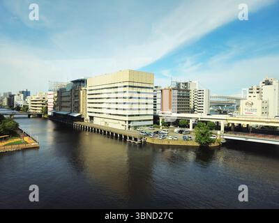 Front de mer du quartier portuaire de Tokyo avec blocs de bureaux et pont Rainbow distant Banque D'Images