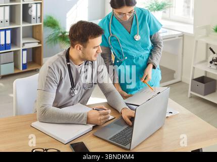 Homme médecin et infirmière aidant à faire du travail papier, discutant des résultats des tests des patients Banque D'Images