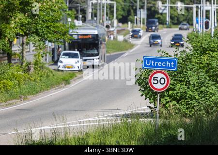Un panneau d'entrée de la ville néerlandaise pour Utrecht avec une limite de vitesse de 50 km/h, situé le long d'une route très fréquentée avec circulation et verdure luxuriante. Banque D'Images