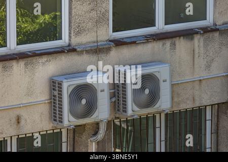 Vieux climatiseurs endommagés nécessitant un entretien et fongicides accrochés au mur extérieur d'un bâtiment d'utilité publique, panne de climatisation, Banque D'Images