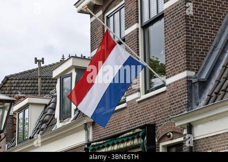 Le drapeau néerlandais flotte en Berne depuis un bâtiment traditionnel en briques, signifiant deuil ou souvenir aux pays-Bas. Banque D'Images