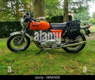 Une moto classique Norton 750 Commando des années 1970 exposée sous des arbres matures dans un cadre vert rural Banque D'Images